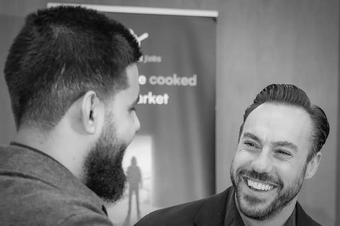 Two guests laughing together at the mixer.