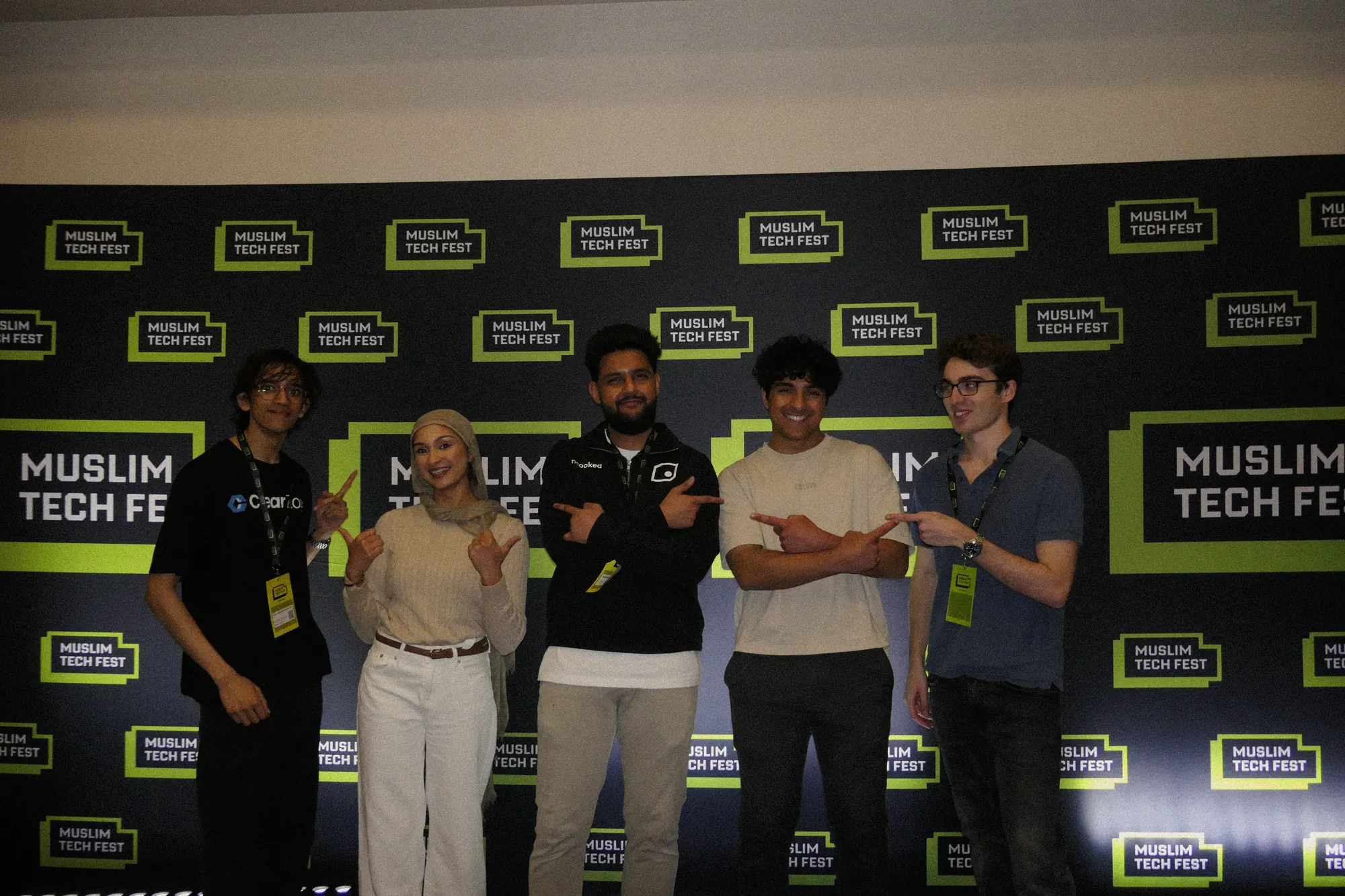 A group of people from Uncooked Labs and the community side by side in front of the Muslim Tech Fest backdrop.