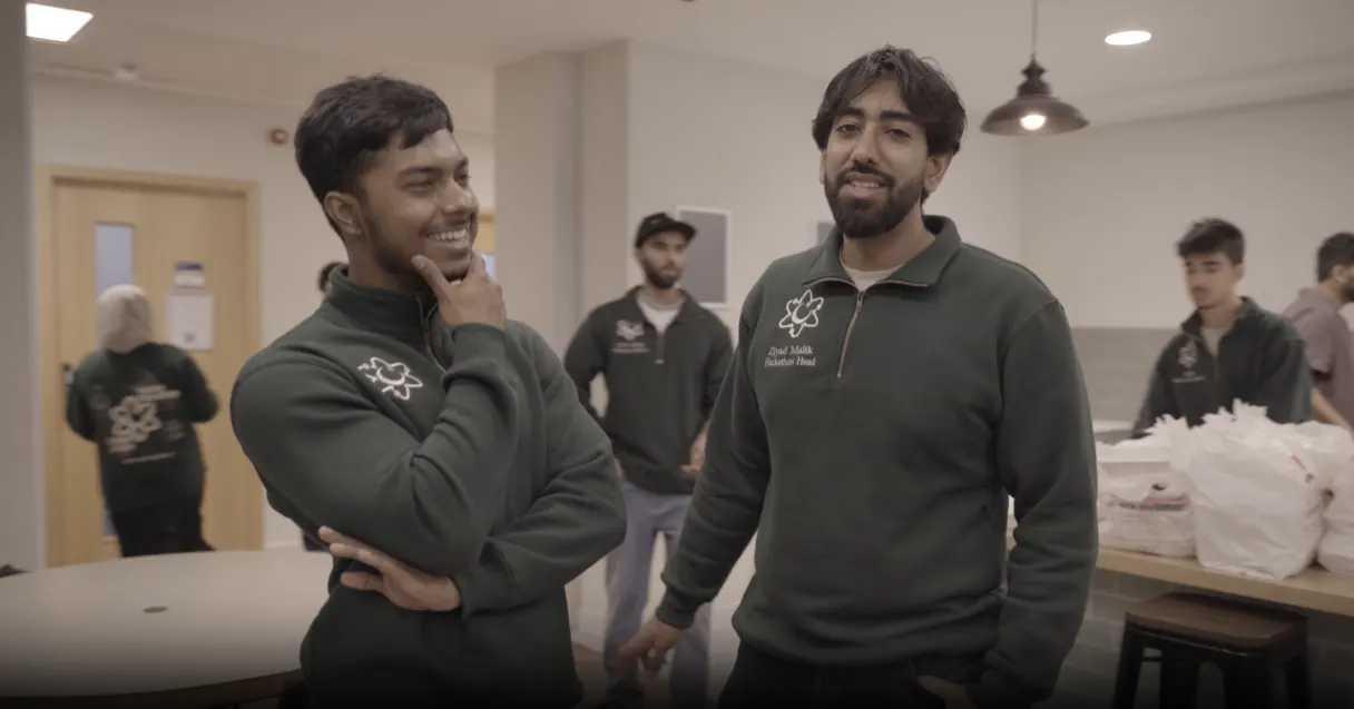 Two people in matching green sweatshirts laughing together at the Haqqathon.