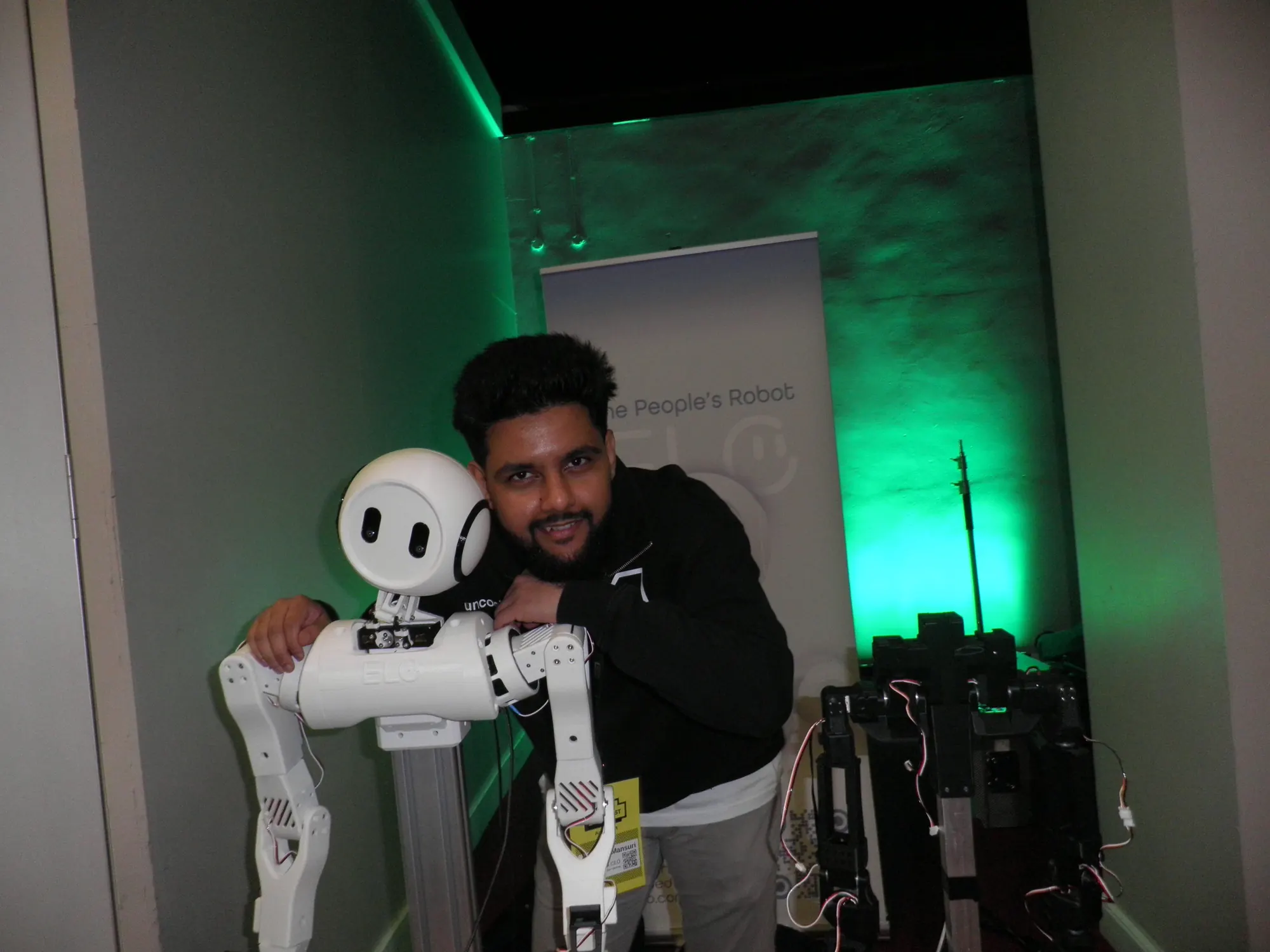 Abdullah, Uncooked Labs founder, leaning on the Elo humanoid robot at Muslim Tech Fest 2026.