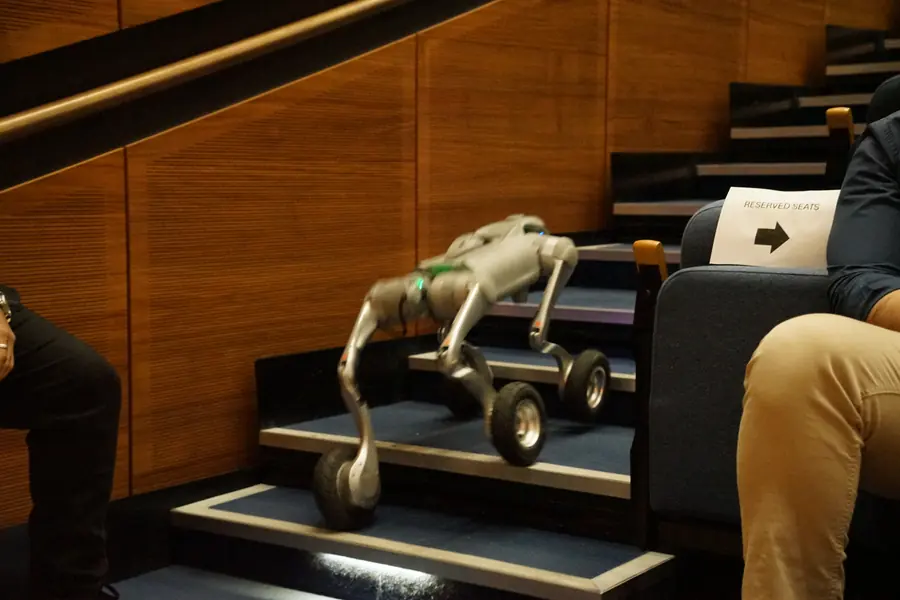 A wheel-legged robot dog climbing a staircase.
